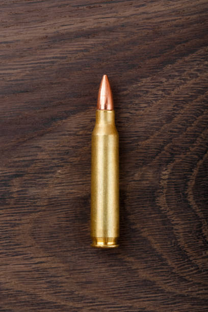 Single rifle bullet on wooden background Single rifle bullet on wooden background. High resolution photo ak 47 bullets stock pictures, royalty-free photos & images