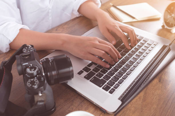 young female photographer checking images on laptop on work desk in home office. professional photographer concept. - fotografia imagem imagens e fotografias de stock