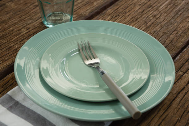 istock Plate with fork and napkin on wooden table 875751200