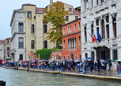 People with umbrellas walking in the rain in Venice, Italy.