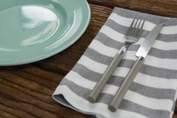 istock Plate with cutlery and napkin on wooden table 875752756