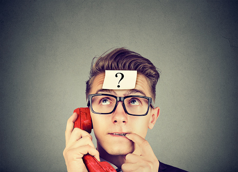 Perplexed young man with question mark having a telephone conversation