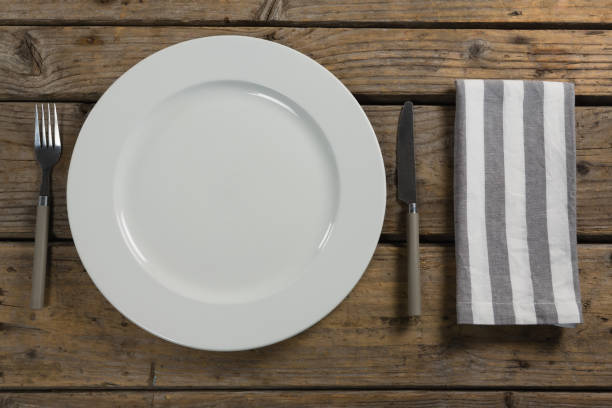 istock Plate with cutlery and napkin on wooden table 875753526