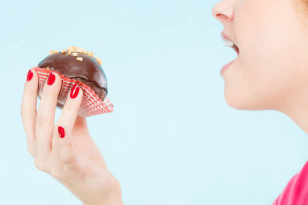 istock Woman holding chocolate cupcake about to bite 875771574