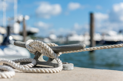 Three different ropes lie around a bollardon the pier of ruegen.