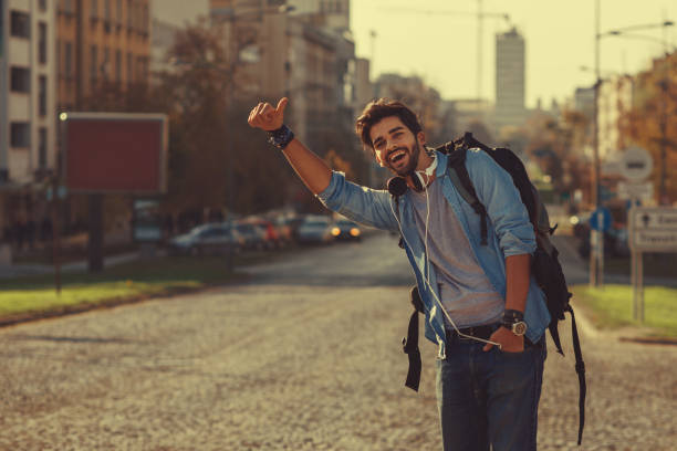 Young man traveler hitchhiking in the city Young man traveler hitchhiking in the city hitchhiking stock pictures, royalty-free photos & images