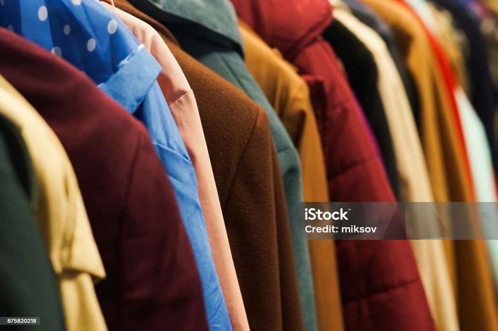Colourful coats in the charity shop. Rack with colourful coats. Charity second hand clothes. Coat - Garment Stock Photo