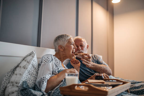 Sharing is caring Elderly couple sharing breakfast in bed bed breakfast pictures stock pictures, royalty-free photos & images