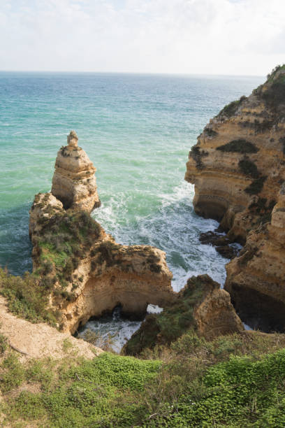 istock upper view on seascape with stunning huge rocks cliffs with seas caves on sandy camilo beach with waves in colorful sunny blue sky with clouds, algarve, portugal 875893126