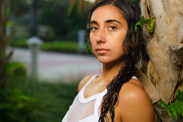 istock Woman posing wet after swimming leaning on a palm tree 875895784