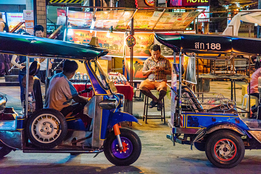 Chiang Mai: Night market street scene of tuk tuks with stalls in the background in the famous Chiang Mai night bazaar on July 30, 2017 in Chiang Mai