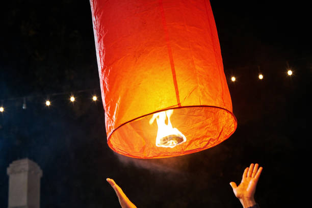 istock people launch a sky lantern on the annual festival (Yi Peng), on dark background 875907630