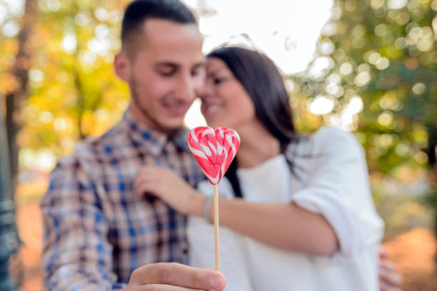 istock Happy couple playing with a heart shape lollipops 875925756
