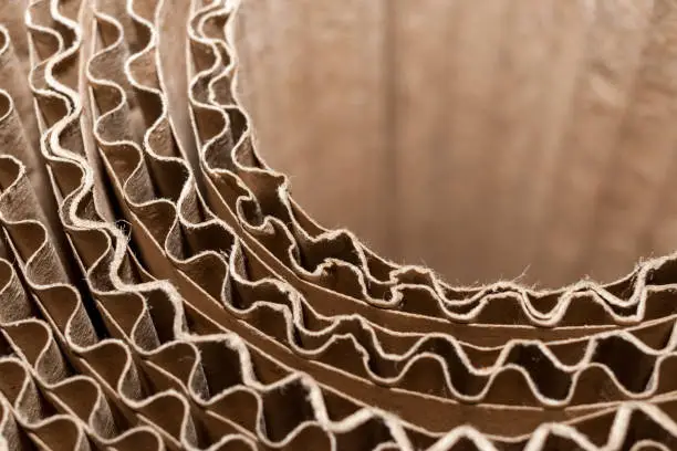 Close-up part of circular coil of corrugated cardboard with wavy layers. Top side view.