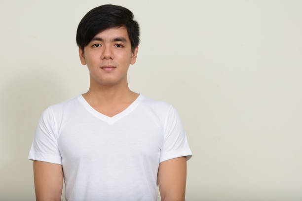 Studio shot of young handsome Asian man wearing white shirt against white background