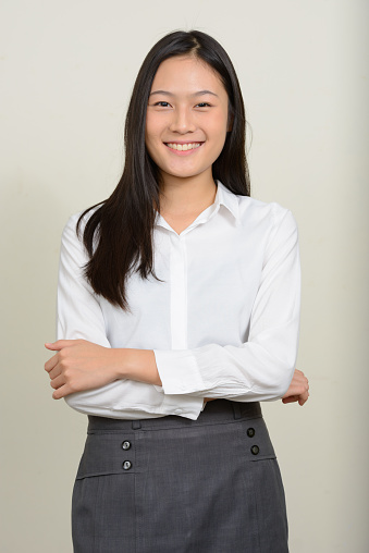 Studio shot of young beautiful Asian businesswoman against white background