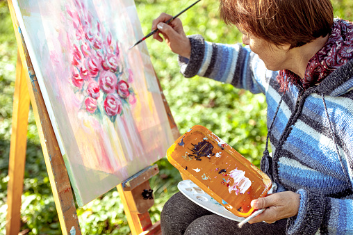 Woman Artist Painting Pink Flowers on the Canvas - Rear View