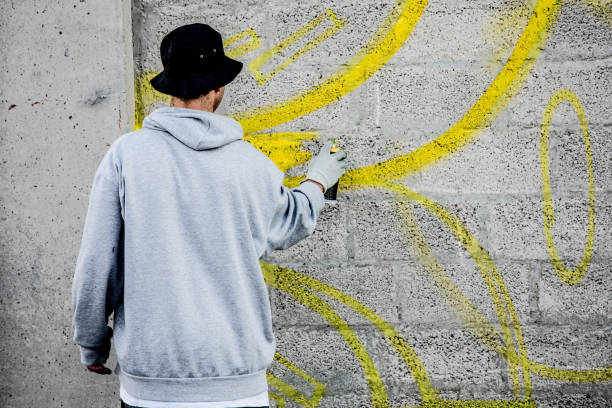 istock Late Teen Graffiti Artist Drawing Graffiti on Wall 875952344