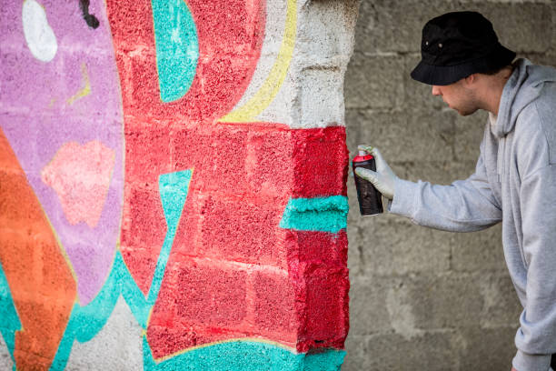 istock Late Teen Graffiti Artist Drawing Graffiti on Wall 875952366