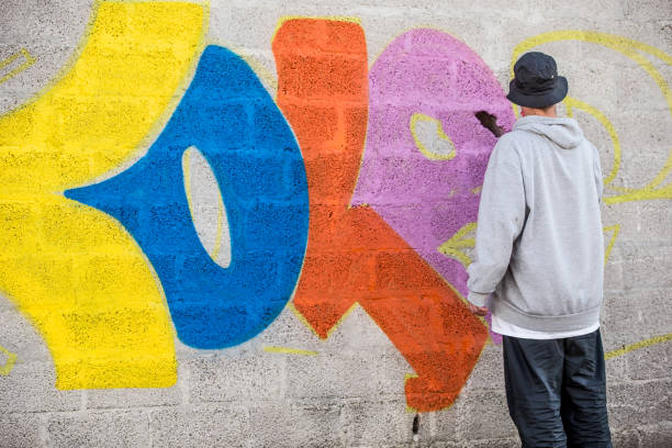 istock Late Teen Graffiti Artist Drawing Graffiti on Wall 875952374
