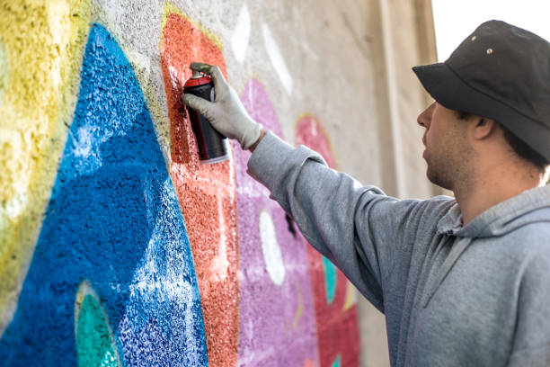 istock Late Teen Graffiti Artist Drawing Graffiti on Wall 875952376