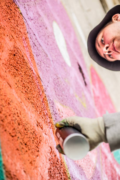 istock Late Teen Graffiti Artist Drawing Graffiti on Wall 875952380