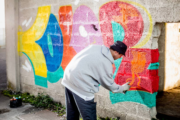 istock Late Teen Graffiti Artist Drawing Graffiti on Wall 875952390