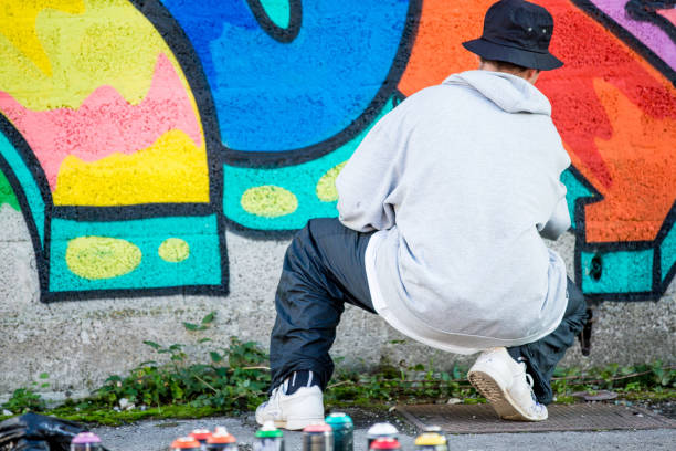 istock Late Teen Graffiti Artist Drawing Graffiti on Wall 875952396