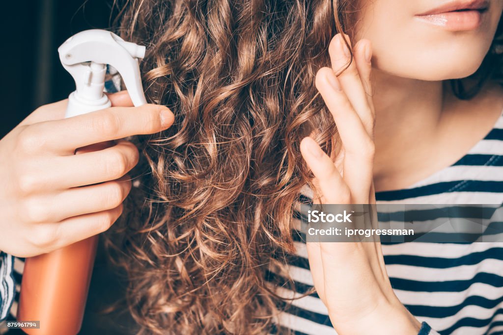 Frau Anwendung Spray auf lockigen braunen Haaren - Lizenzfrei Haarpflege Stock-Foto