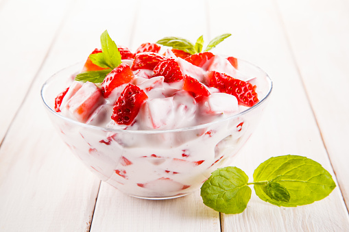 Yogurt with strawberries on wooden background