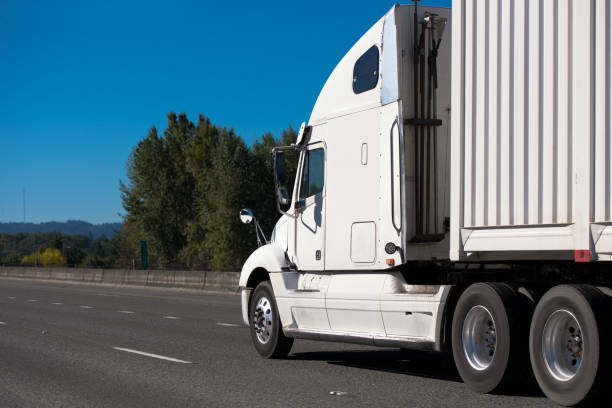 istock White big rig semi truck transporting container along wide interstate highway 875968420