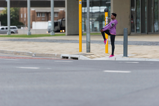 Photo of female runner stretching on sidewalk ready for her morning run