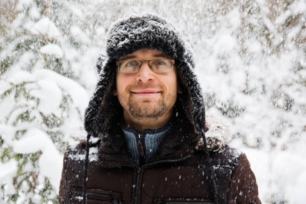 istock Man in fur winter hat with ear flaps smiling portrait 875980540