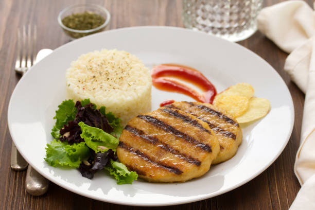 istock grilled hamburger with rice, salad and chips on plate 875984076