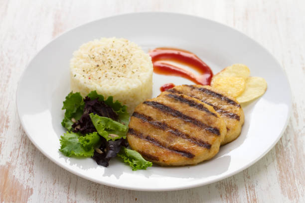 istock grilled hamburger with rice, salad and chips on plate on white wooden background 875984128