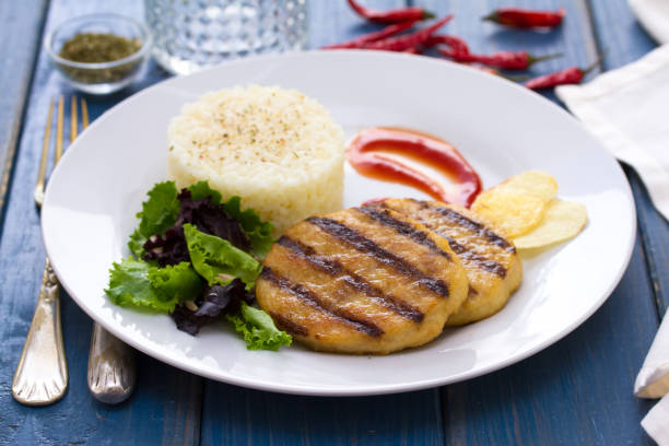 istock grilled hamburger with rice, salad and chips on plate on blue background 875984150