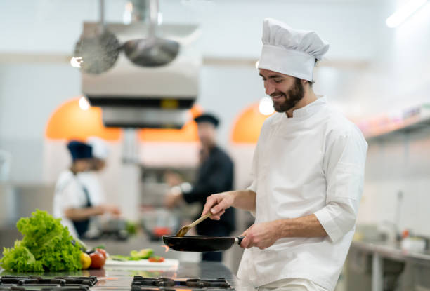 istock Cheerful chef mixing a sauce at the kitchen looking very happy and smiling 875991884