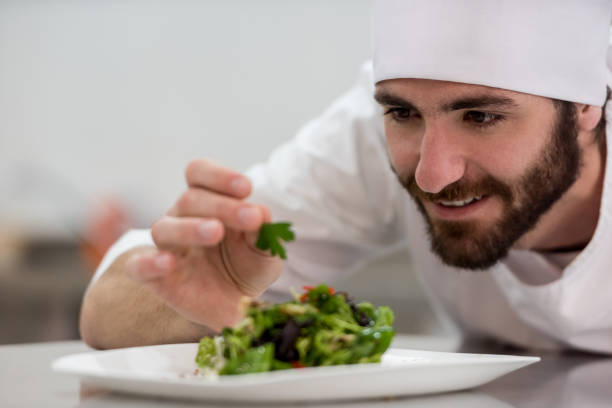 istock Cheerful chef adding details to the meal he just prepared smiling 875991906