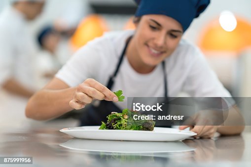 istock Female student at a gourmet institute finishing the details of a salad she just made 875991956