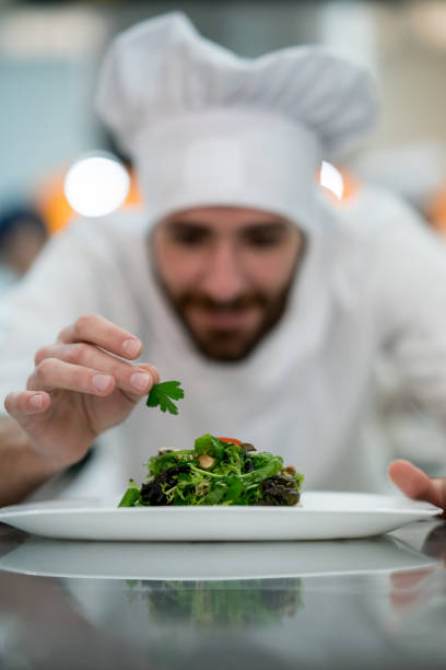 istock Young chef adding details to a salad he just prepared looking happy 875992000