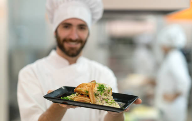 istock Young male chef holding a delicious meal he prepared smiling 875992006