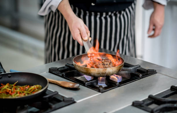 istock Unrecognizable chef using a frying pan to flambe a meat 875992056