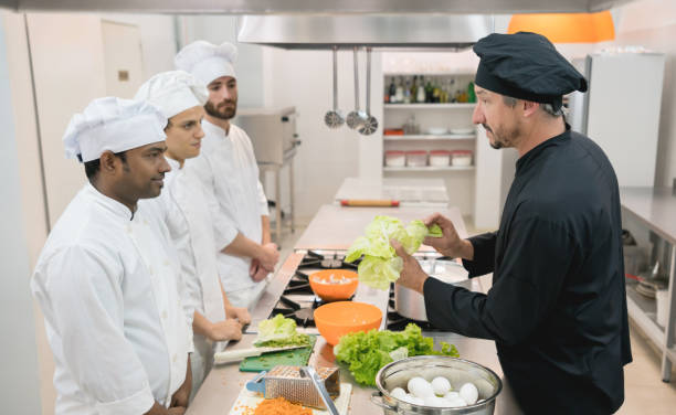 istock Chef teacher showing a fresh lettuce to his students and everyone paying attention 875992318