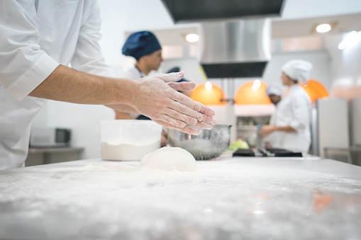 Unrecognizable male chef kneading dough to make pasta at an italian gourmet restaurant