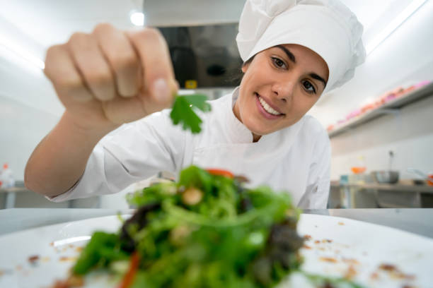 istock Beautiful happy female chef adding details to a salad at a restaurant's kitchen 875992410