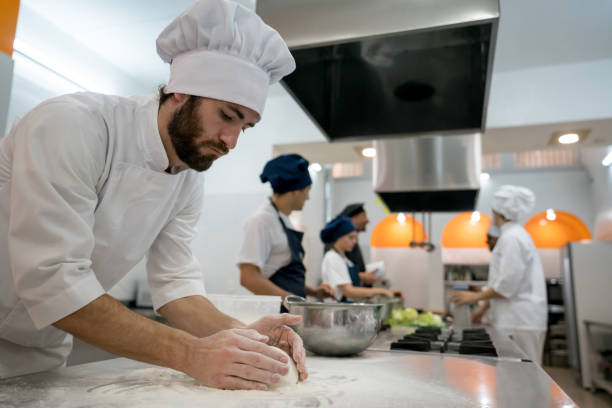 istock Male chef at an italian restaurant kneading dough looking very focused 875992456