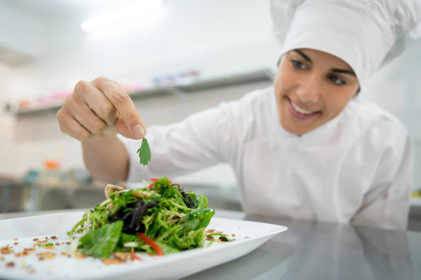 istock Cheerful pretty chef decorating a salad and looking very happy 875992500
