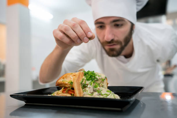 istock Young chef adding spices to a meal ready to serve looking very focused 875992504
