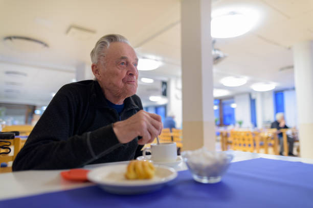 Portrait of senior man relaxing while eating at the cafeteria of nursing home in Turku, Finland