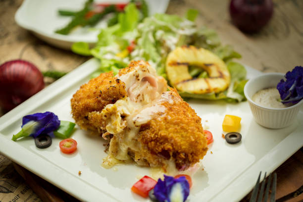 Stuffed roll of chicken with cheese and sage on white plate